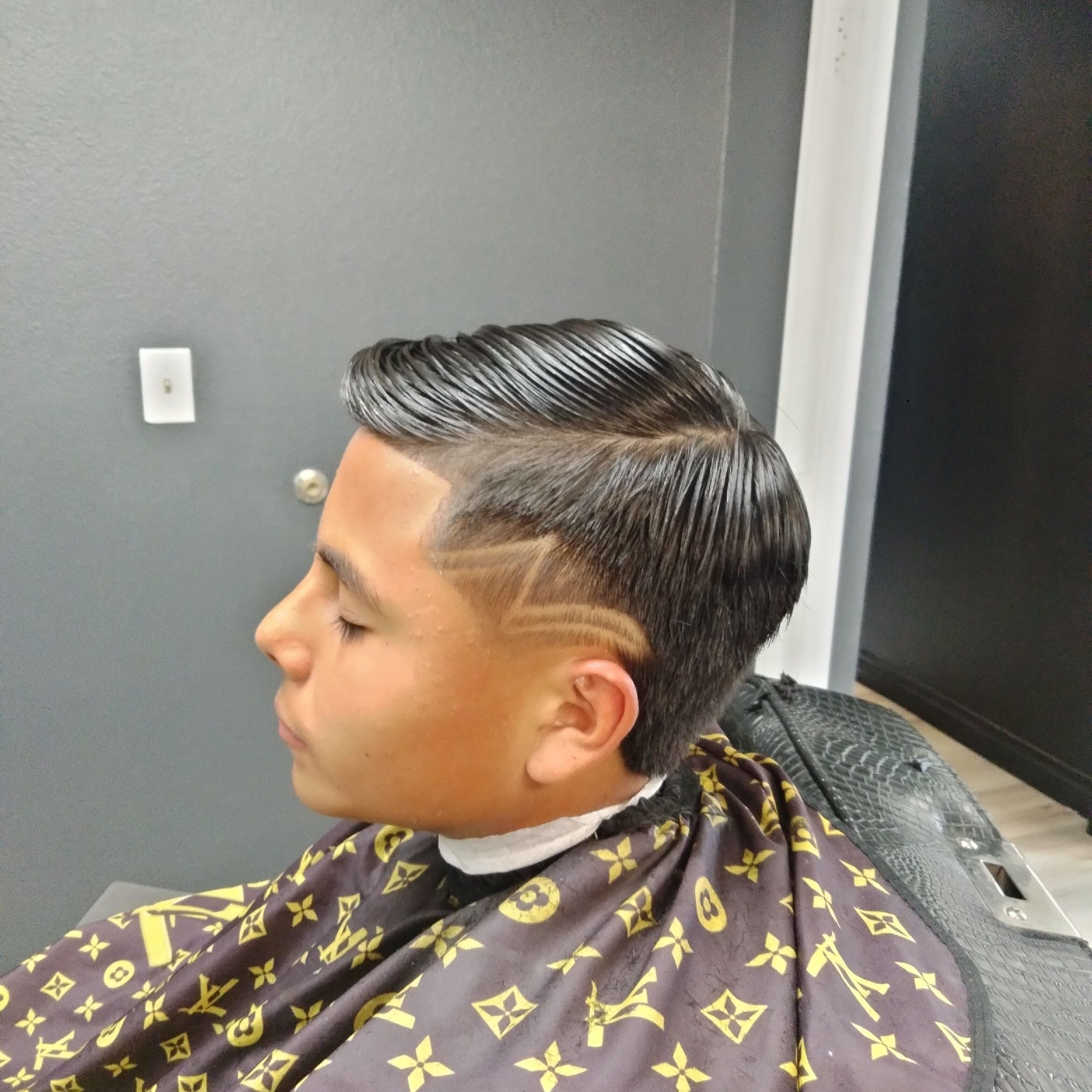 Slick comb-over with V-design hard line and taper fade.