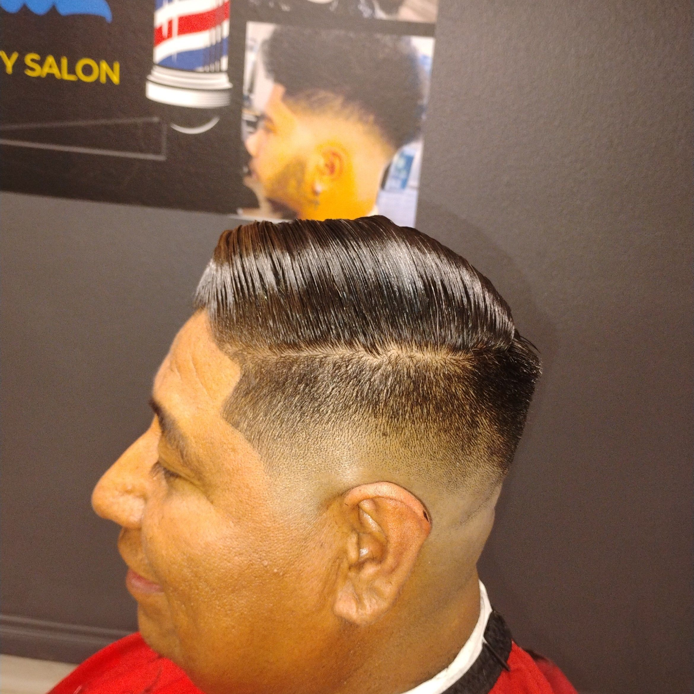 Slick pompadour with sharp side-part and clean fade.