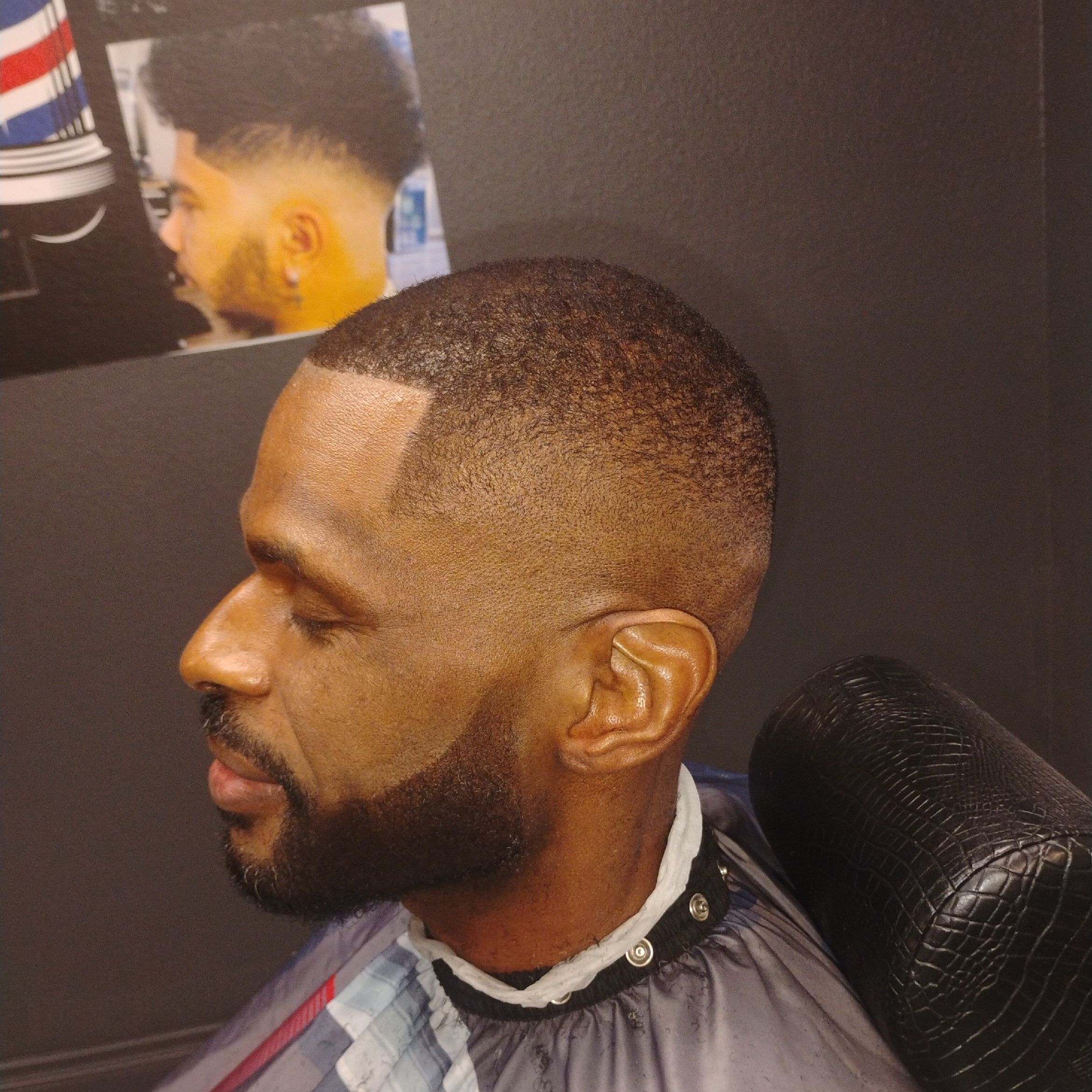 Bald skin fade with full beard line-up — clean side profile.